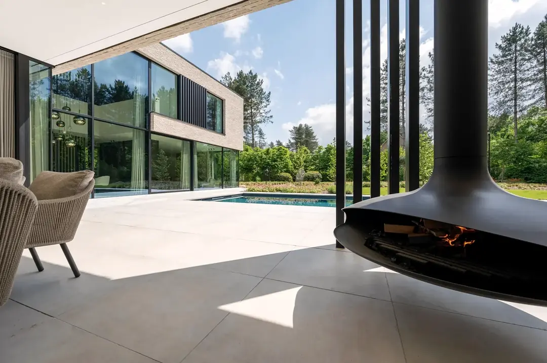 Terrasse couverte avec cheminée suspendue, ouverte sur la piscine