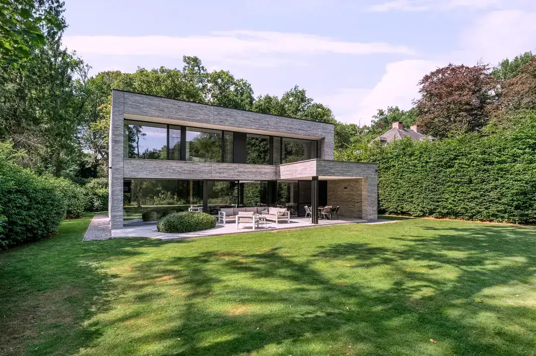 Maison du parc, volumes en pierre grise sur pelouse à Kapellen